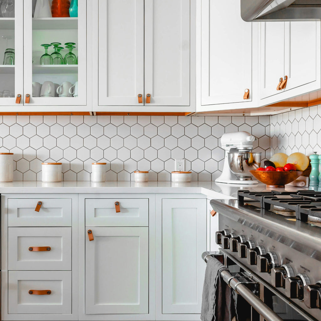 White Shaker kitchen cabinets with hex tile backsplash and leather pulls – classic modern interior design
