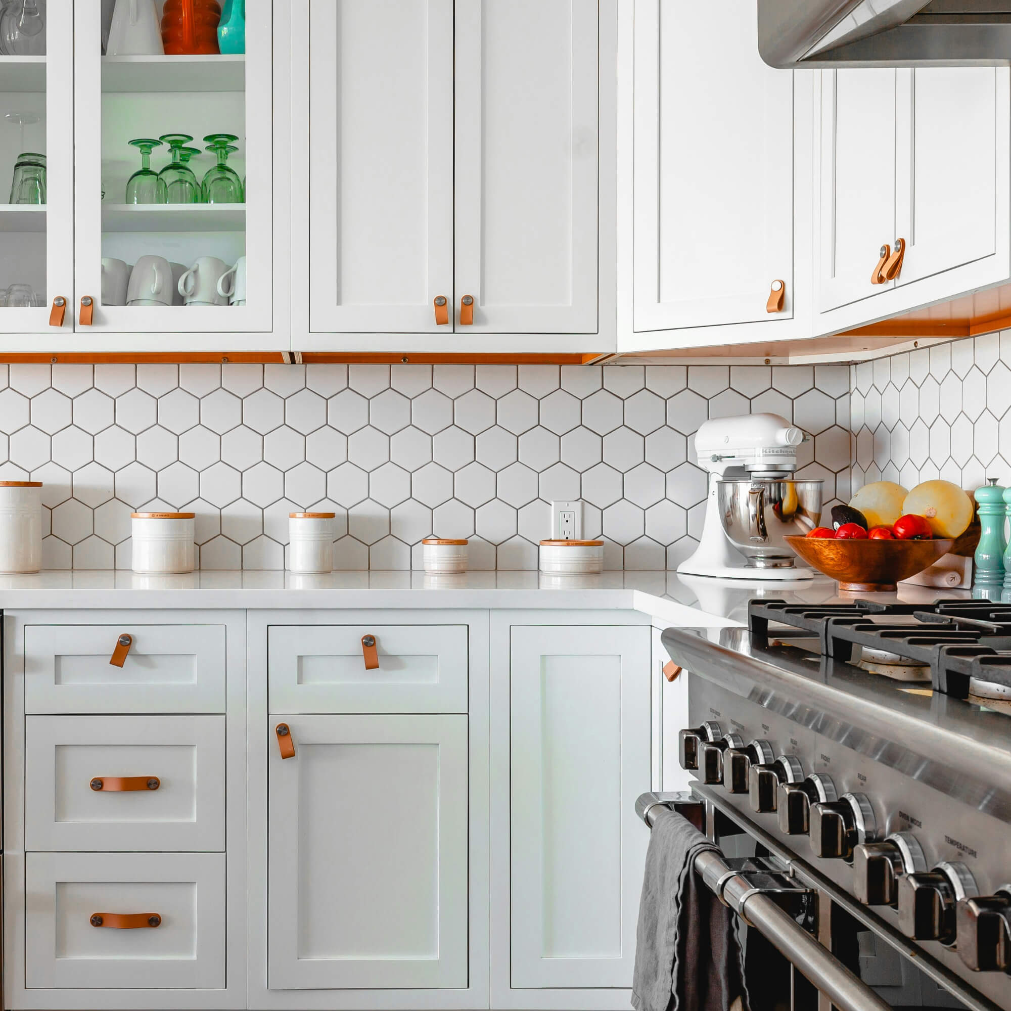 White Shaker kitchen cabinets with hex tile backsplash and leather pulls – classic modern interior design